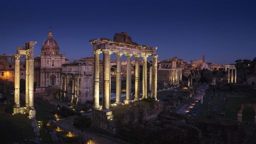 A beautiful shot of the roman forum under a dark blue sky at night time