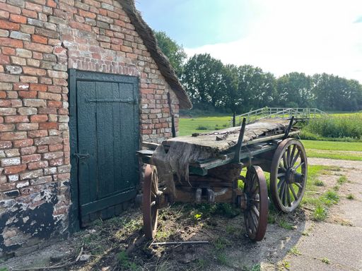 An old wooden peasant cart in front of a brick barn