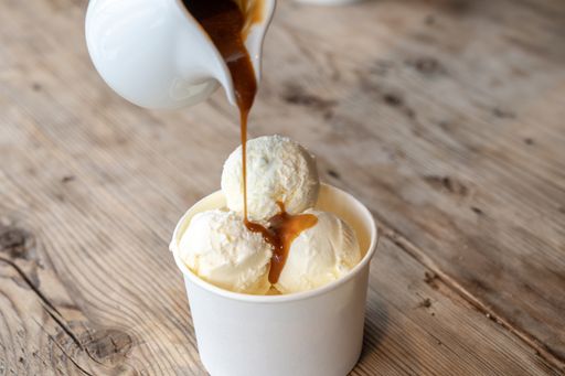Three balls of white ice cream with caramel syrup on a rough wooden table