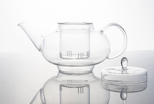 A closeup shot of an empty glass teapot against a white background
