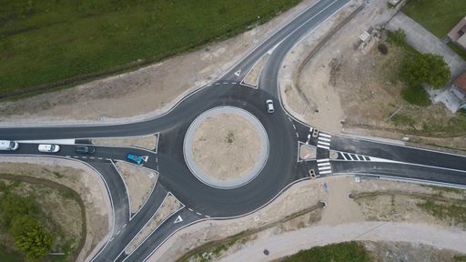An aerial shot of a ring road surrounded by a field in the daylight