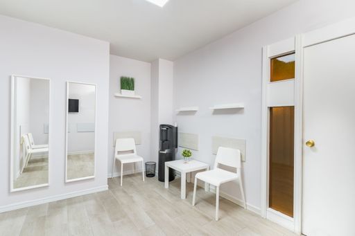Bright and clean waiting area with chairs and table in a modern medical or wellness clinic interior.