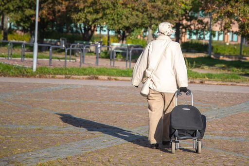 An old woman carrying a bag with wheels