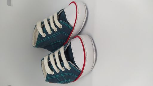 A vertical shot of a pair of fashionable stylish baby boy converse sneakers isolated on a white background