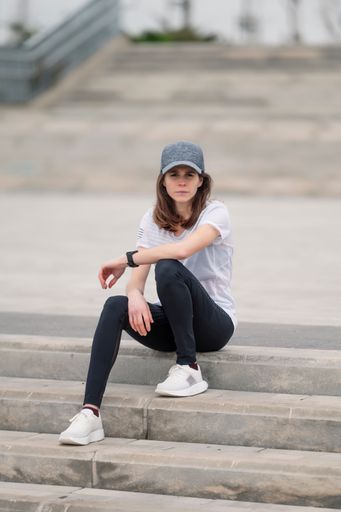 A young sporty female jogger resting on the stone stairs