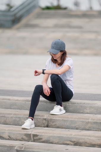 A young sporty female jogger resting on the stone stairs