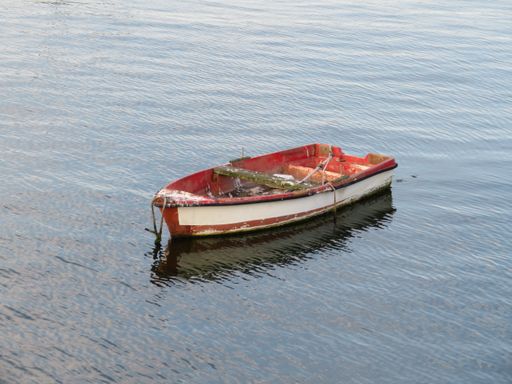 A small weathered boat reflected in the water