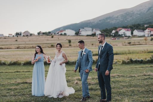 The cheerful married couple with their friends having fun in a hayfield on the wedding day