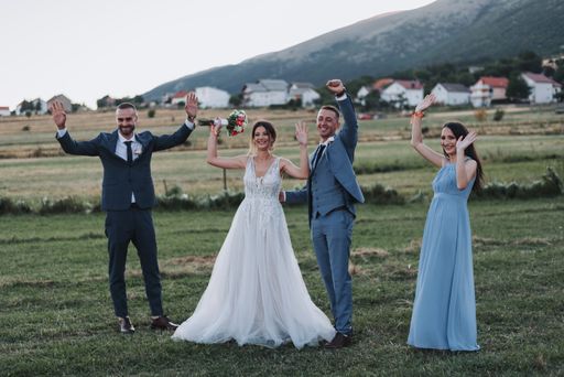 The joyful married couple with their friends having fun in a hayfield on the wedding day