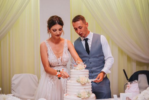 The beautiful bride and the groom from Bosnia and Herzegovina cutting the wedding cake in the hall