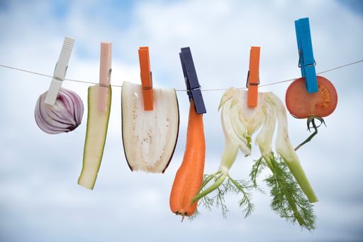A closeup shot of various vegetables hanging from clothes begs on a washing line