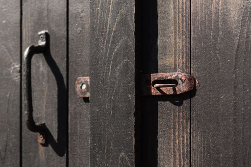 A closeup shot of an old wooden barndoor with a rusty metallic lock