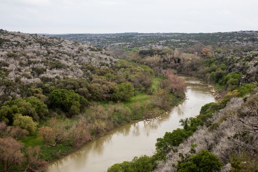 A scenic view of canal flowing between forest with trees against cloudy sky