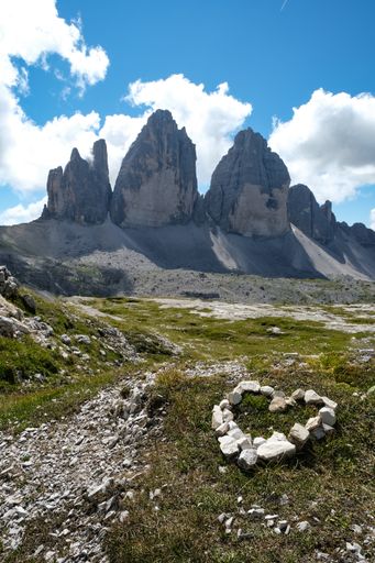 A vertical shot of Drei Zinnen Nature Park with a small heart from pebbles on the ground in Italy