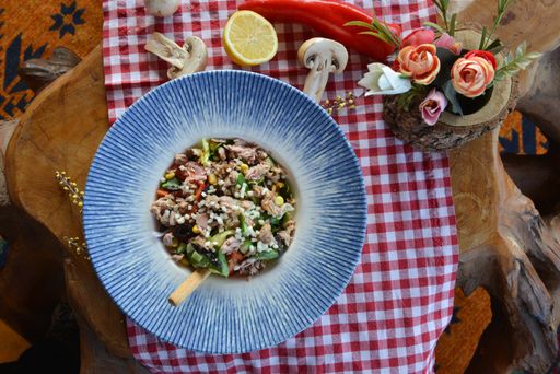 A top view of a bowl of tuna and vegetable salad on the table in a restaurant