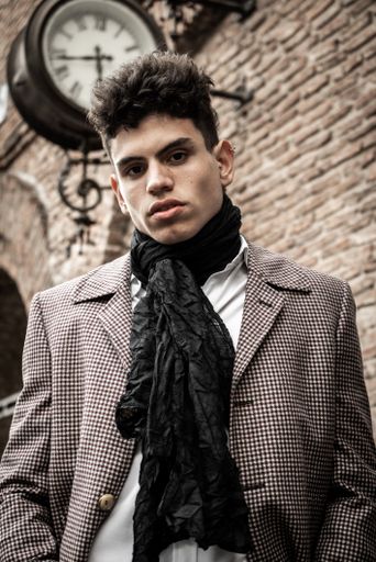 A vertical shot of a handsome Hispanic guy on a brick wall background