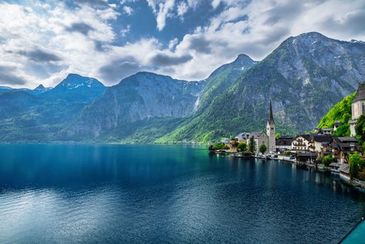 Scenic view of Hallstatt village with alpine mountains and lake under a cloudy sky in Austria.