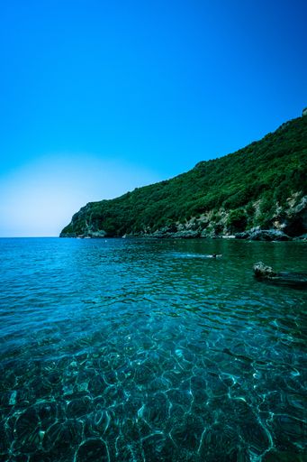 A vertical shot of the beautiful clean sea surrounded by high green mountains