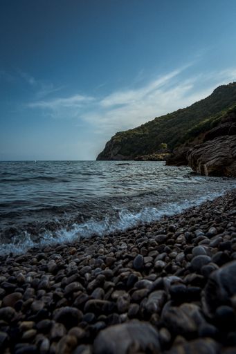 A vertical shot of rock formations by the sea under a beautiful cloudy sky