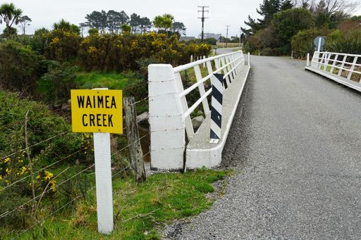 A yellow sign saying 'Waimea creek' before the bridge