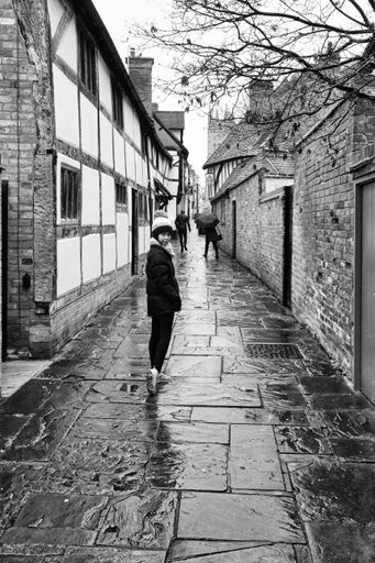 A young girl walks along a wet cobbled path in Warwick, Warwickshire, England.
