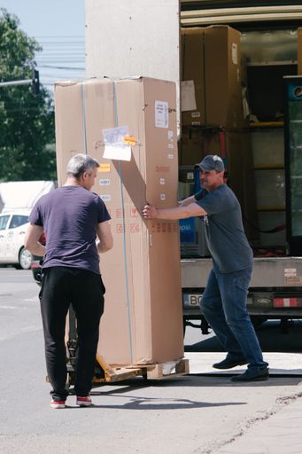 Two middle aged men carrying a big box
