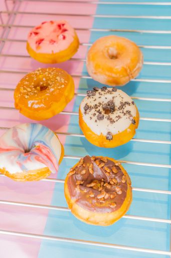A top view of colorful tasty doughnuts on a metal net
