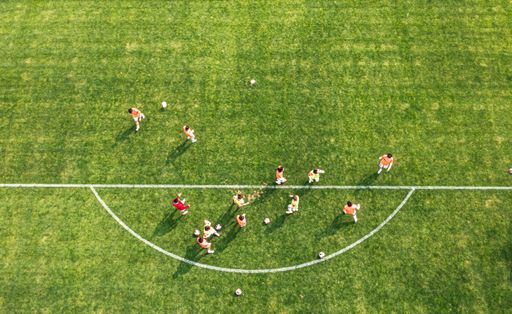 Aerial view of a soccer team practicing on a green field, showcasing teamwork and sportsmanship.