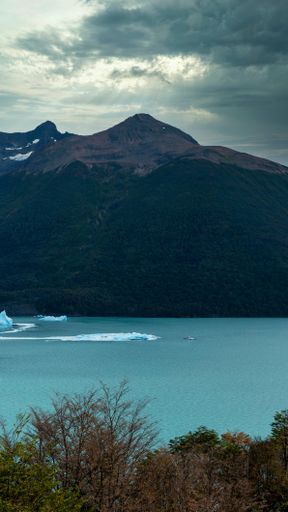the boat is very small next to the huge mountains and blocks of ice.