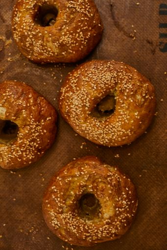 A vertical shot of fresh out-of-oven bagels on a parchment paper
