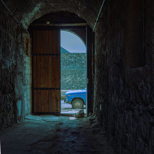 A vertical shot of a wooden door of an old stone corridor in Gyumri, Armenia