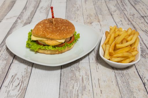 A closeup of a delicious burger with fries on the wooden table.