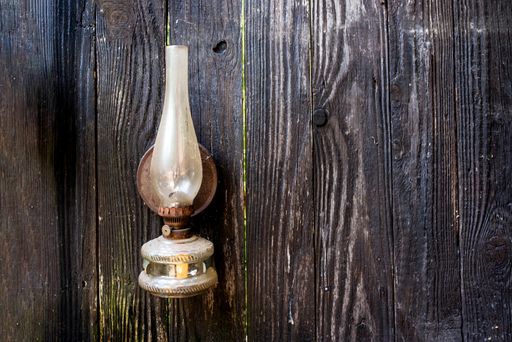 An old kerosene lamp hanging on a wooden wall