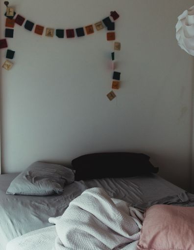 A cozy bedroom with polaroid shots hanging on the gray wall