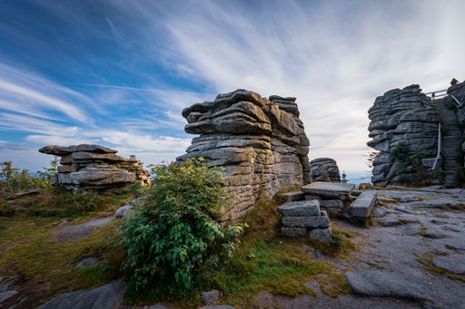 A Beautiful scenery of pole of stones amid green grass field and green trees under a cloudy blue sky