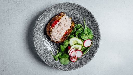 A top view of the delicious stuffed potato with sauce on the plate on the gray surface