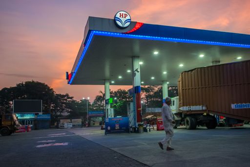 A man walking by a gas station in the early morning with the sun rising in Mumbai, India