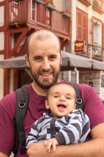 A vertical shot of a cheerful Caucasian father with his playful baby boy on a summer vacation