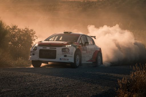 A white racing car driving very fast as the sand and dust coming out of its wheels in Granada, Spain