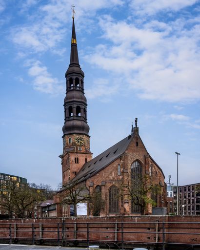 St. Catherine's Church in Hamburg, Germany, with its iconic spire against a partly cloudy sky.