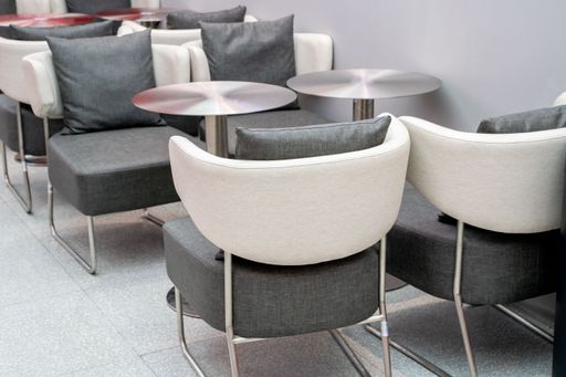 Modern lounge seating area with sleek grey and white chairs and round tables in an indoor setting.