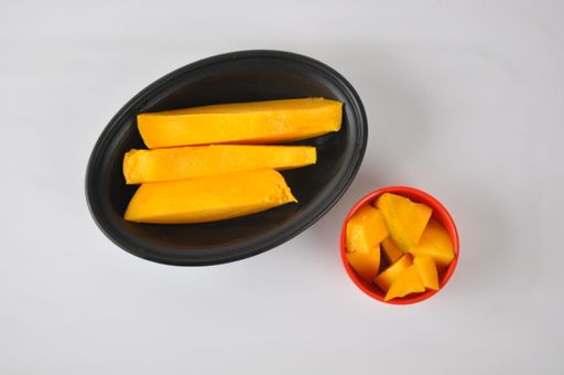 The mango slices in the black plate and a small red bowl isolated on a white background