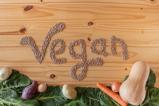 The Word "vegan" formed with legumes on wooden background