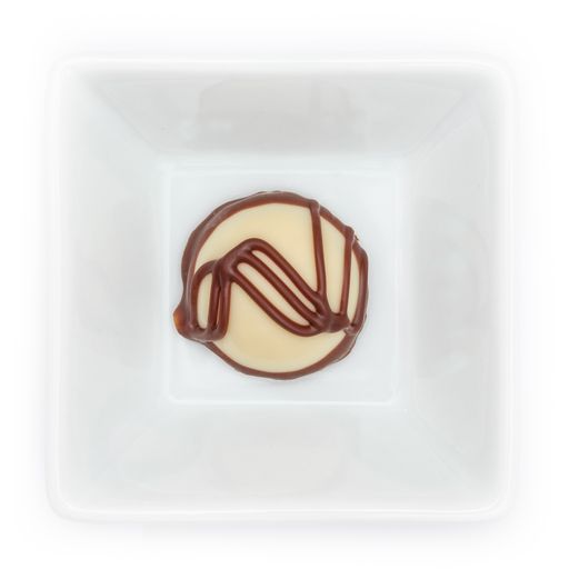 A closeup of white chocolate praline in a bowl on a white background