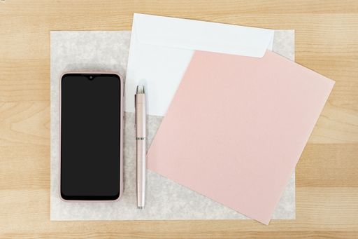 A mockup of a cellphone and business card with wooden desk background