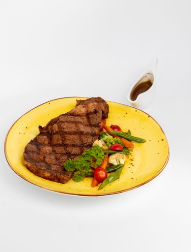 A vertical shot of a delicious steak with vegetables in a yellow plate on a white background