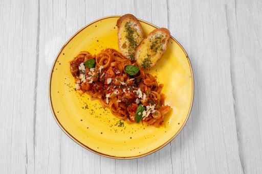 A top view of a delicious pasta dish with tomato sauce, basil and cheese in a yellow plate
