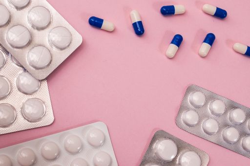 A high angle shot of pills on a pink background - healthcare concept