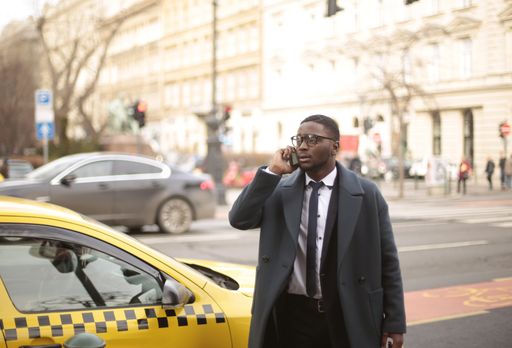 An African American person talking on the phone while crossing the street