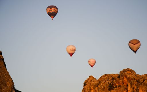 Air balloons soar over Cappadocia's rocky landscape at sunrise.